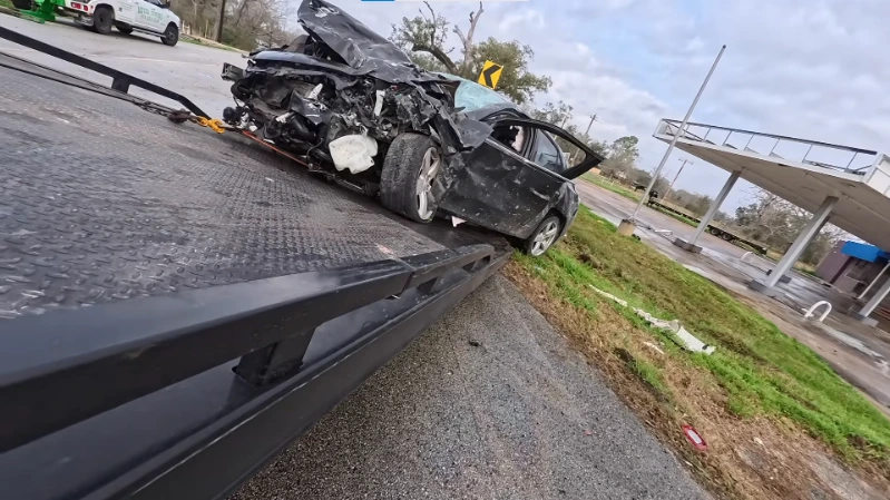 Tow truck recovering a vehicle after a curve accident on a wet rural road near Asheville NC