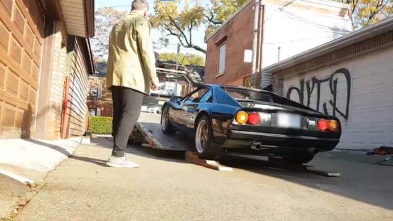 Flatbed tow truck loading a lowered sports car in a residential driveway in Asheville NC